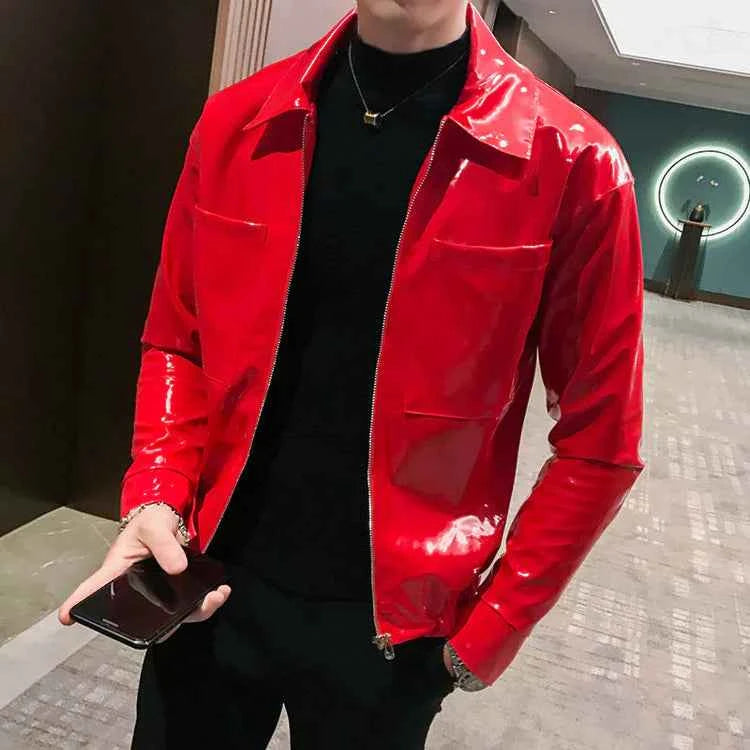 Man wearing shiny red leather jacket with black turtleneck, holding phone in modern interior